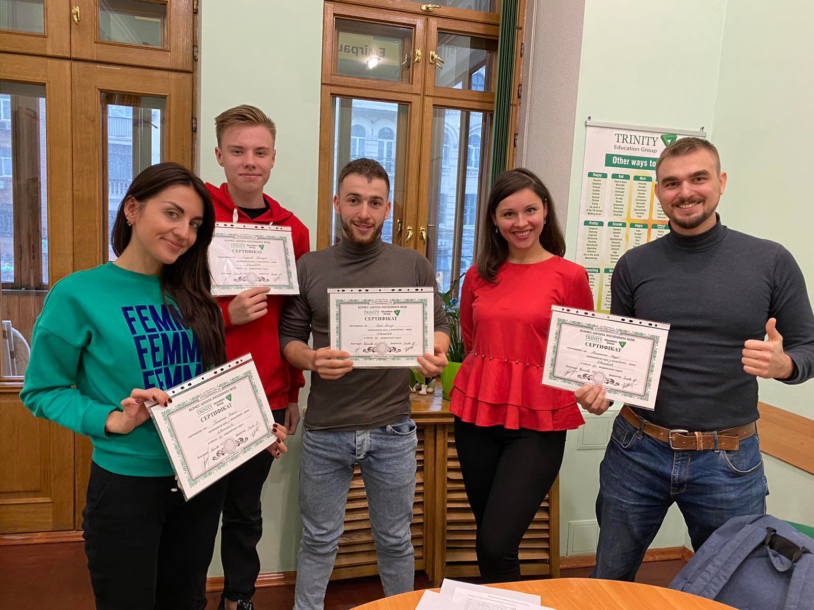 Trinity learners holding course certificates in a classroom