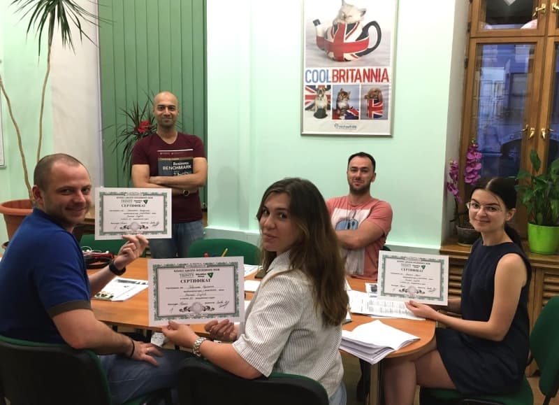 Trinity learners gathered around a classroom table with certificates